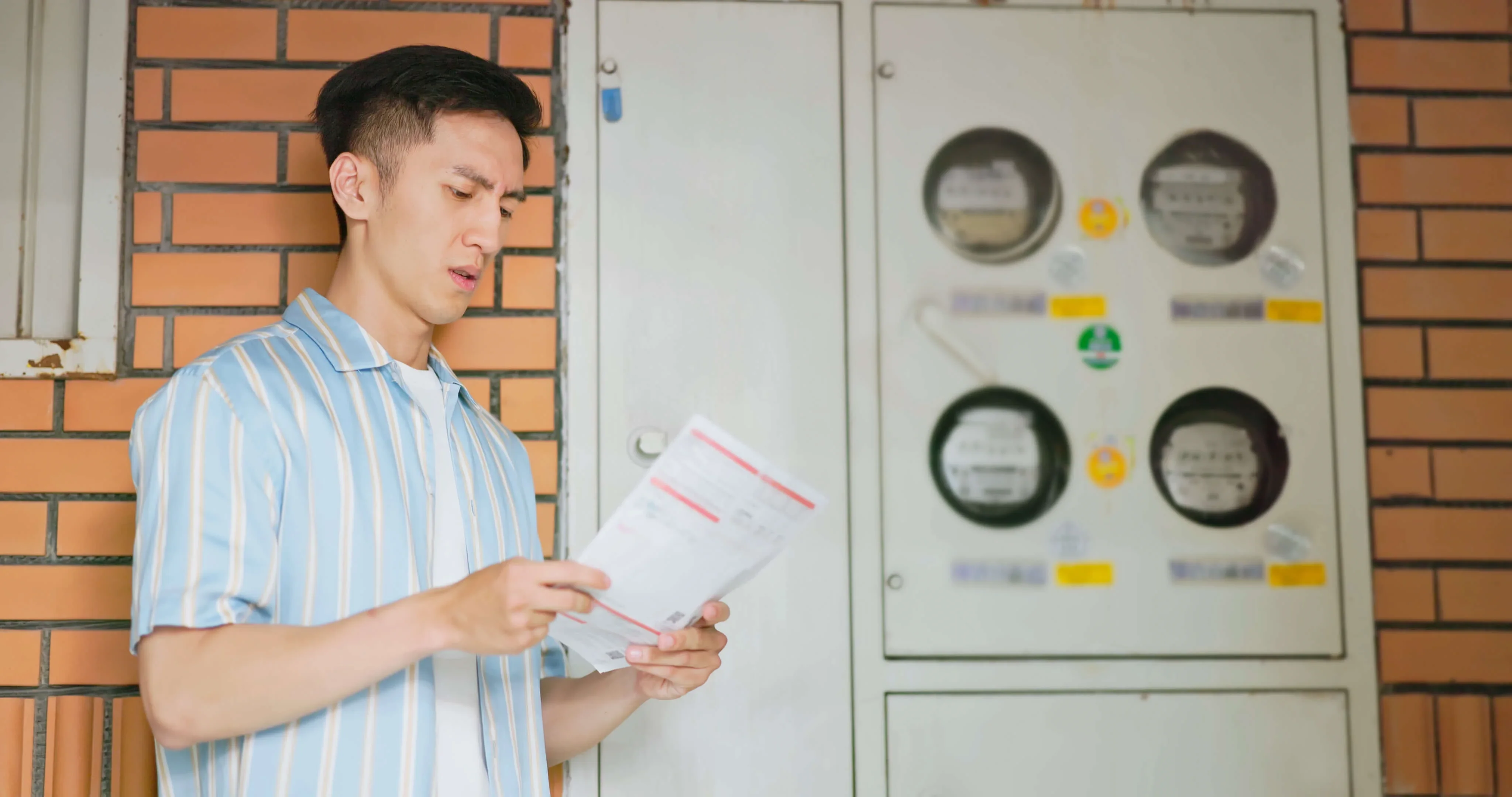 A business owner looking at an energy bill as he stands by his commercial half hourly energy meters